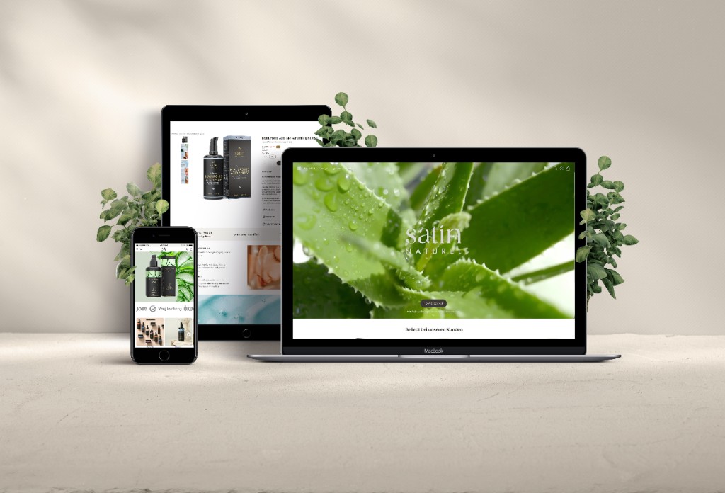 Satin Naturel storefront on laptop, tablet and phone — responsive views with product detail and botanical styling
